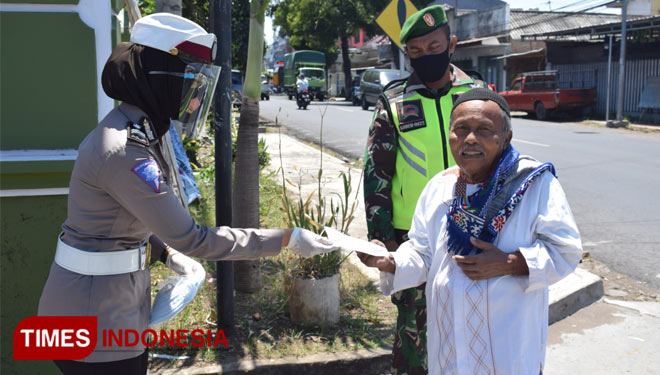 Anggota kepolisian Polres Bondowoso bersama TNI saat memberikan masker untuk warga yang hendak melaksanakan ibadah shalat Jumat (FOTO: Moh Bahri/TIMES Indonesia).