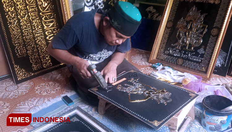 Suparno painting a Wayang (puppet show doll) with glue gun. (Photo: Totok Hidayat/TIMES Indonesia)