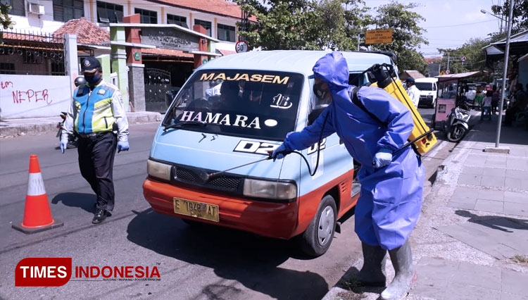 Petugas menggunakan APD lengkap menyemprotkan cairan disinfektan pada angkutan umum (FOTO: Ayu Lestari/TIMES Indonesia) 