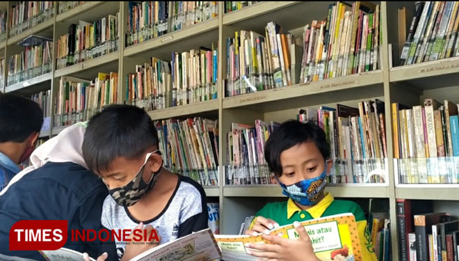 Sejumlah anak tengah membaca buku di perpustakaan keliling dalam kegiatan Hari Kunjung Perpustakaan yang digelar GenBI Jember di Desa Glundengan, Jember, Senin (14/9/2020). (Foto: GenBI Jember for TIMES Indonesia)