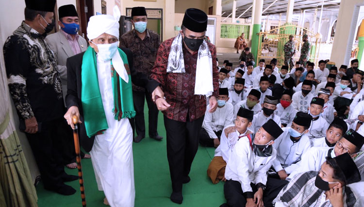 TGH Turmudzi menggandeng Menag RI Fachrul Razi saat memasuki ruang pertemuan silaturahim antara Menteri Agama dengan santri Qomarul Huda, Kamis (17/). (Foto: dokumentasi Kemenag)
