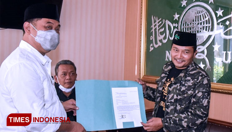 Cabup Banyuwangi, Yusuf Widyatmoko menyerahkan surat Non Aktif dari pengurus Mustasyar kepada Ketua PCNU Banyuwangi, KH Ali Makki Zaini. (FOTO: Syamsul Arifin/TIMES Indonesia)