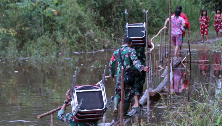 Satgas TMMD Reguler 109 Kodim 1205 Sintang saat membantu warga dengan menjeberangi jembatan sementara (Foto: ajp.TIMES Indonesia)