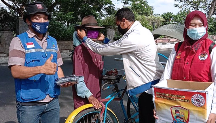 Petugas dari BPBD dan Dinsos Kota Kediri saat membagikan masker kepada tukang Becak di depan kantor pos Kota Kediri. (Foto: Kominfo Kota Kediri)