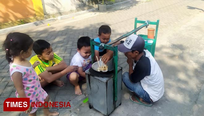 Heri saat melayani anak-anak dengan jual pentol goreng (Rohmadi/TIMES Indonesia)