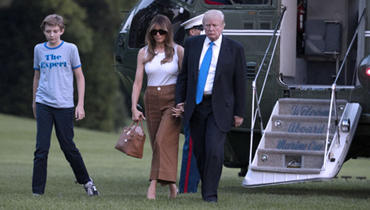 Presiden Donald Trump, ibu negara Melania Trump, dan putra mereka,  Barron Trump saat berjalan dari Marine One melintasi South Lawn ke Gedung Putih di Washington. (FOTO: AP)