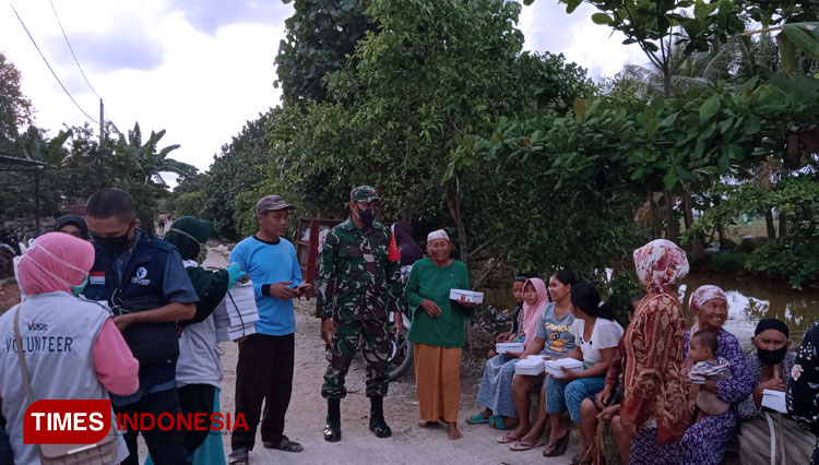 Warga Dusun Gebangsari menerima nasi kotak dari relawan, sebagian warga lainnya mengantri air untuk diisi ke jerigen masing-masing. (Foto: Hermawan Septianto/TIMES Indonesia)