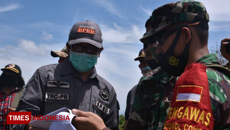 Plt Bupati Jember KH Abdul Muqit Arief menyimak penjelasan dari anggota TNI terkait pelaksanaan TMMD ke-110, Sabtu (17/10/2020). (Foto: Dody Bayu Prasetyo/TIMES Indonesia)