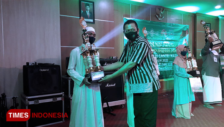 M. Iwan menerima trophy dari Kabid Kebudayaan Disdikbud Kota Probolinggo, Sardi. (FOTO: Iqbal/TIMES Indonesia)