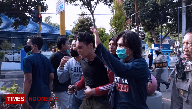 Polisi mengamankan pendemo yang diduga sebagai provokator aksi pelemparan batu. (FOTO: Agung Sedana/TIMES Indonesia)