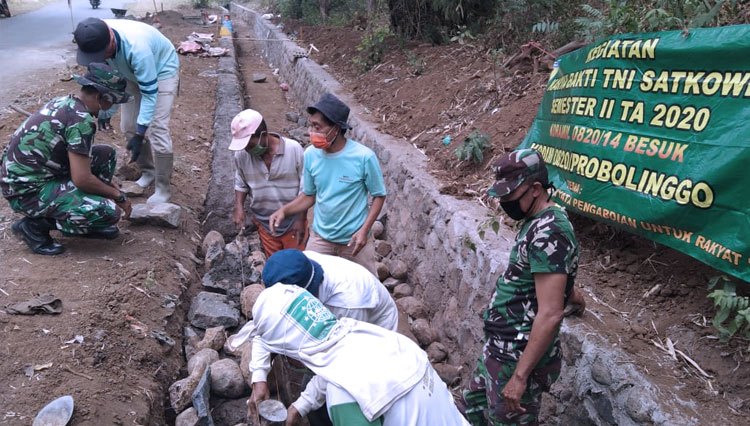 Anggota Koramil 0820/14 Besuk, kerja bakti bersama warga memperbaiki saluran irigasi. (FOTO: Sumartono for TIMES Indonesia)