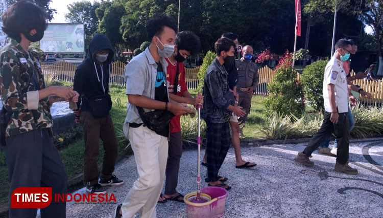 Para remaja yang bermain skeatboard di area terlarang Monumen Gerbong Maut mendapatkan sanksi sosial kebersihan dan mengepel monumen. (FOTO: Moh Bahri/TIMES Indonesia).