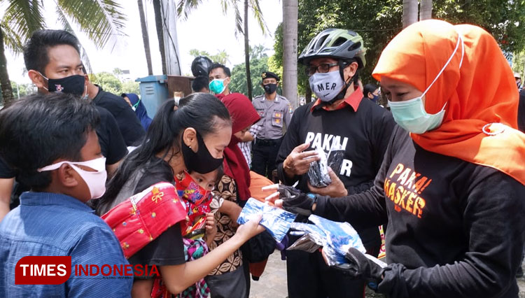 Gubernur Jatim Khofifah Indar Parawansa (berkerudung orange) membagikan masker kepada masyarakat Jember saat gowes, Minggu (15/11/2020). (Foto: Imam Nawawi/TIMES Indonesia)
