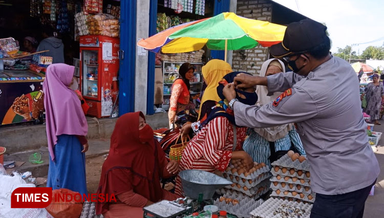 Kapolsek Proppo bersama anggotanya saat memberikan sosialisasi dengan berbagi Masker gratis di pasar Polowijo Desa Panaguan Kecamatan Proppo, Kabupaten Pamekasan. (Foto: Akhmad Syafi'i/TIMES Indonesia)