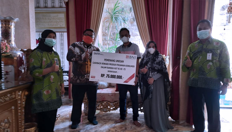 Head of Consumer Banking Wilayah Malang, M. Safri Hidayat, menyerahkan hadiah senilai Rp75 juta berupa cashback kepada seorang nasabah BNI Probolinggo, Kamis (19/11/2020). (FOTO: BNI)