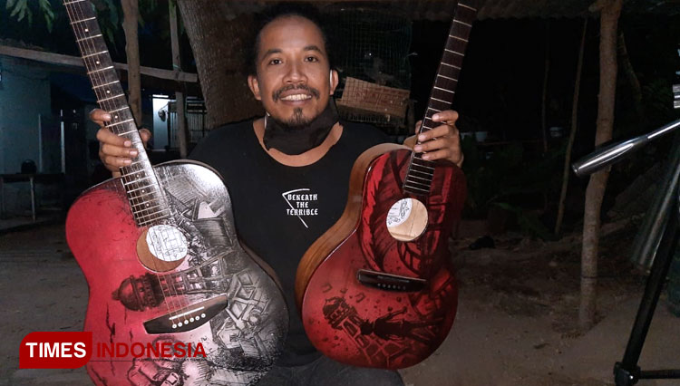Musisi sekaligus pengerajin gitar, Andika Risma atau Achi The Box memperlihatkan gitar hasil buatanya yang bertema Likuefaksi Balaroa (Foto: Anang Prasetio/TIMES Indonesia)
