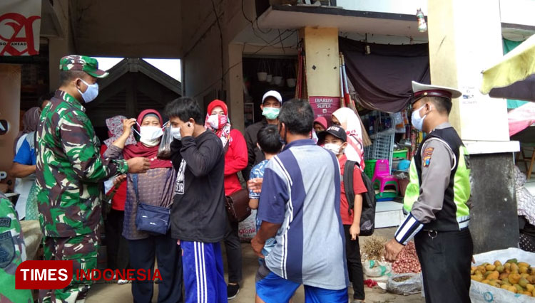Anggota Koramil Slahung dan imstansi terkait bagikan masker kepada warga di pasar. (Foto:Humas Kodim/Times Indonesia)