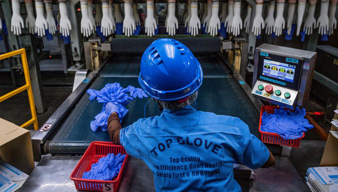 Seorang pekerja memeriksa kualitas sarung tangan karet sekali pakai di pabrik Top Glove, Malaysia. (Foto: Mohd Rasfan / AFP)