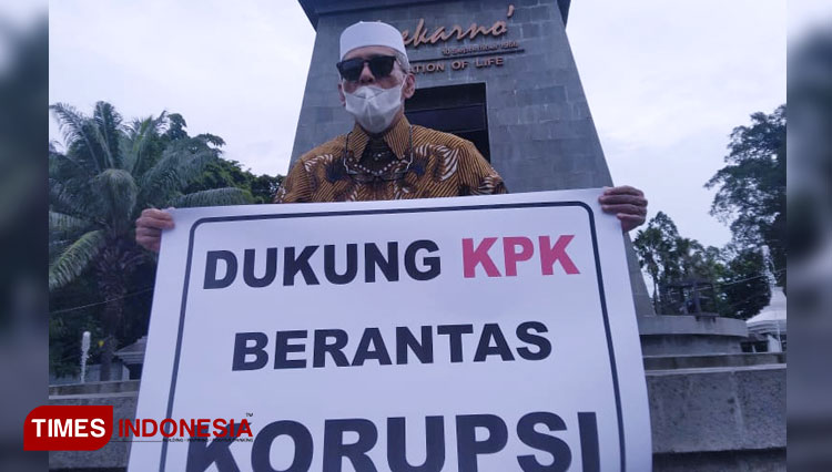 Habib Hasan Mulachela membentangkan poster dukungan terhadap KPK di depan Patung Soekarno Manahan, Senin (7/12/2020). (foto: Muhamad Shidiq/TIMES Indonesia)