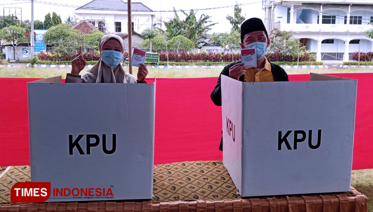 Gus Riza Bersama Istri, Neng Bilqis saat menunjukkan surat suara di bilik TPS 17. (FOTO: Riswan Efendi/TIMES Indonesia)