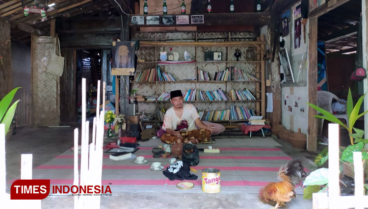 Pemilik dan pendiri padepokan Nyai Surti di Kabupaten Bondowoso berpakaian khas Nusantara dengan sarung dan kopiah hitam. Ia juga tampak memberi makan hewan peliharaannya. (FOTO: Moh Bahri/TIMES Indonesia)