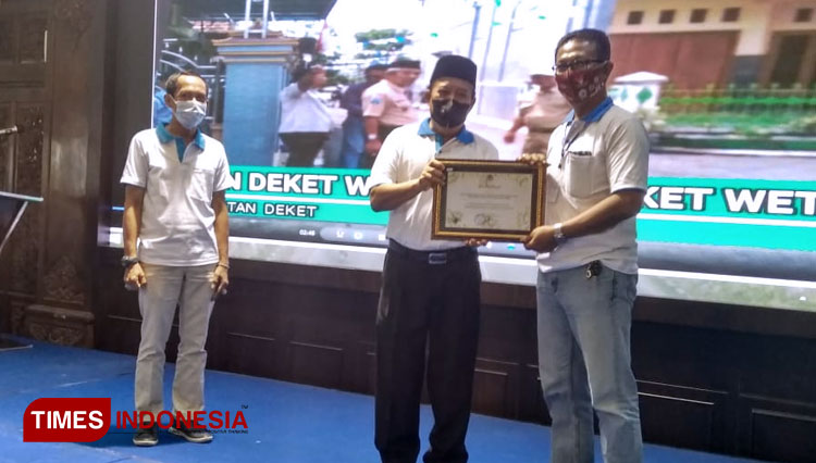 Bupati Lamongan, Fadeli memberikan penghargaan Desa Proklim kepada Kepala Desa Deketwetan, Kusbianto S Putro, di Pendapa Lokatantra Lamongan, Selasa (15/12/2020) (Foto: Moch. Nuril Huda/TIMES Indonesia)