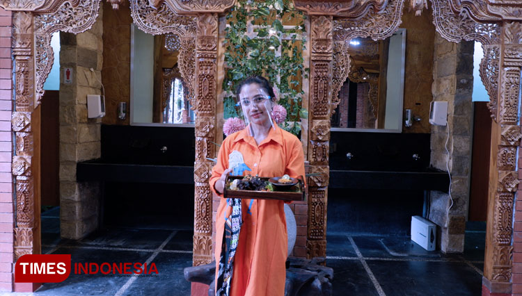 Marketing Manager, Rieke Fransiska, memamerkan salah satu menu andalan Neo Kedaton Resto and Catering Malang dengan latar belakang interior kayu jati. (Foto: Naufal Ardiansyah/TIMES Indonesia)