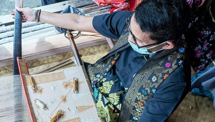 Menteri Pariwisata Sandiaga Uno saat mencoba menenun kain saat kunjungan ke Desa Sade Sasak, Lombok, NTB, Jumat (15/1/2021). (foto: Kemenparekraf RI) 