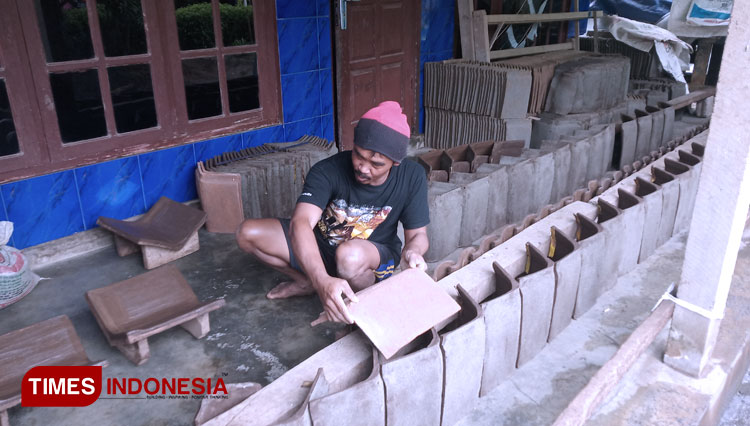 Rohmad sedang menata genteng yang habis dicetak (Foto: Totok Hidayat/TIMES Indinesia)