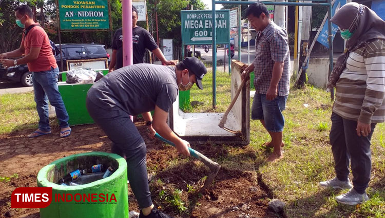 Bapak Literasi Kota Cirebon Zaenal Muttaqin sedang membersihkan rumput liar di halaman yang akan dibuat taman (Foto : Ayu Lestari / Times Indonesia)