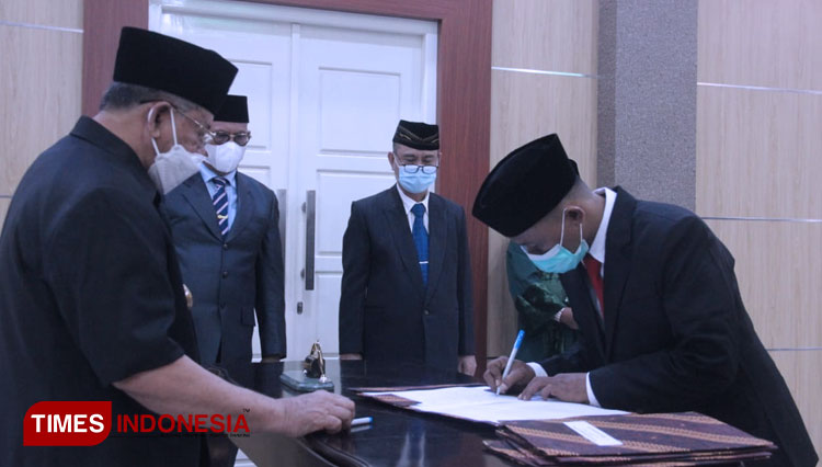Anggota Komisi Informasi Awat Halim membubuhi tandatangan disaksikan oleh Gubernur KH Abdul Gani Kasuba. (Foto: Wahyudi Yahya/TIMES Indonesia)