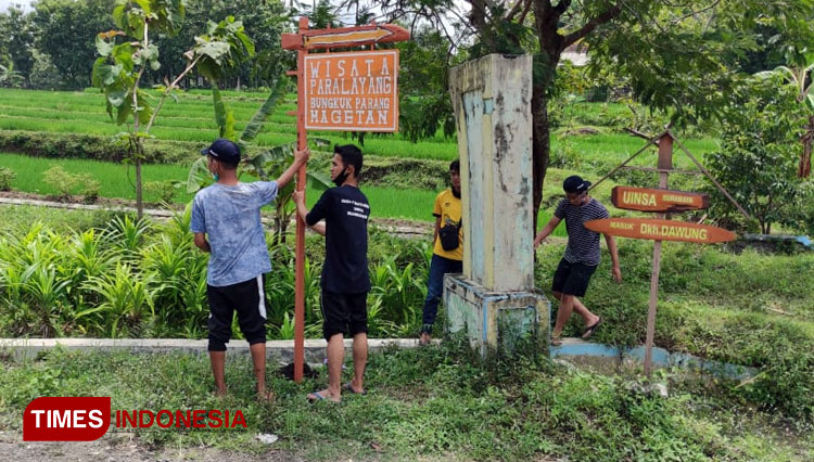 Mahasiswa KKNT Unipma bersama warga memasang papan penunjuk jalan menuju spot paralayang. (Foto: KKNT Unipma/TIMESIndonesia)