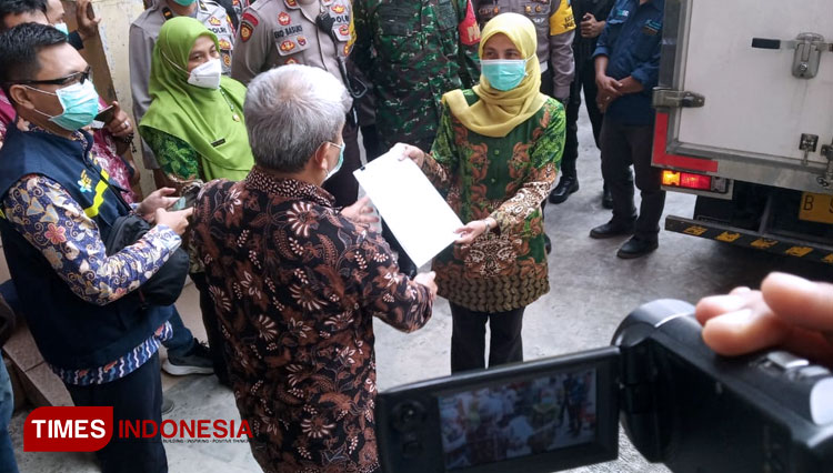 Plt Kepala Dinkes Jember saat menerima berkas acara penyerahan vaksin Sinovac dari Dinkes Jatim pada Selasa (26/1/2021) di Gudang Farmasi, milik Dinkes Jember. (Foto: Muhammad Faizin/TIMES Indonesia)