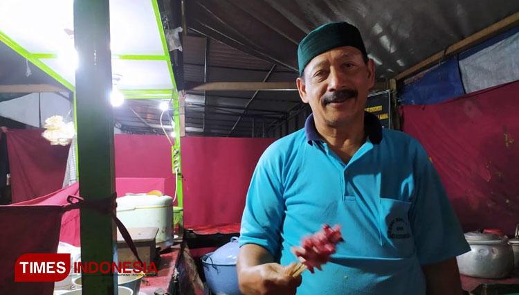 Muhsin bin Ali pemilik sekaligus juru masak kuliner sate legendaris 'Bang Muhsin' yang ada sejak 1975 di Bondowoso. Tampak ia sedang melayani langsung pelanggan. (FOTO: Moh Bahri/TIMES Indonesia)