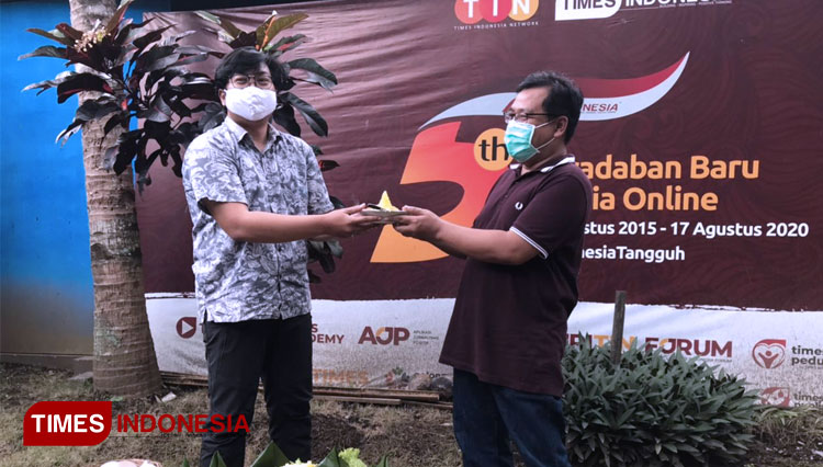 GM e-Koran TIMES Indonesia Imadudin menyerahkan potongan tumpeng kepada CEO TIMES Indonesia Khoirul Anwar. (Foto: Rizky Kurniawan Pratama/TIMES Indonesia)