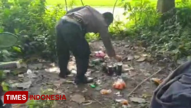 Polisi saat mengamankan sejumlah botol miras milik pemuda yang sedasng asyik pesta di hutan jati.(FOTO: Dicko W/TIMES Indonesia)
