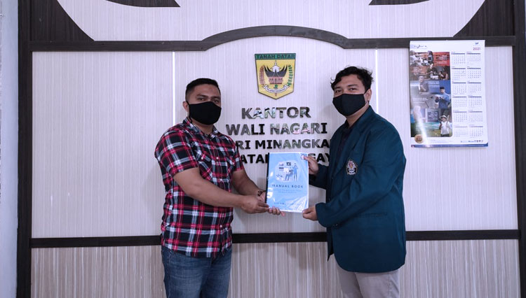 Mahasiswa KKN Undip, Faridi menyerahkan manual book aplikasi pengarsipan berbasis website pada Sekretaris Nagari Minangkabau di Tanah Datar, Sumatera Barat, Rabu (17/2/2021). (Foto: Dok Undip)