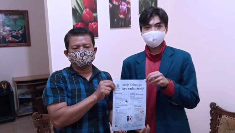 Mahasiswa KKN Undip, Muhammad Chaerul Afik menyerahkan poster sosialisasi pentingnya arsip keluarga di Tembalang, Semarang, Rabu (17/2/2021). (Foto: Dok Undip)