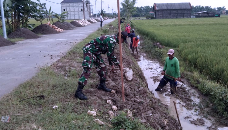 Sertu Asikin membantu warga Desa Jubel Kidul, Kecamatan Sugio membuat saluran irigasi sepanjang 100 meter, Rabu (17/2/2021). (FOTO: Dok.Pendam Brawijaya)