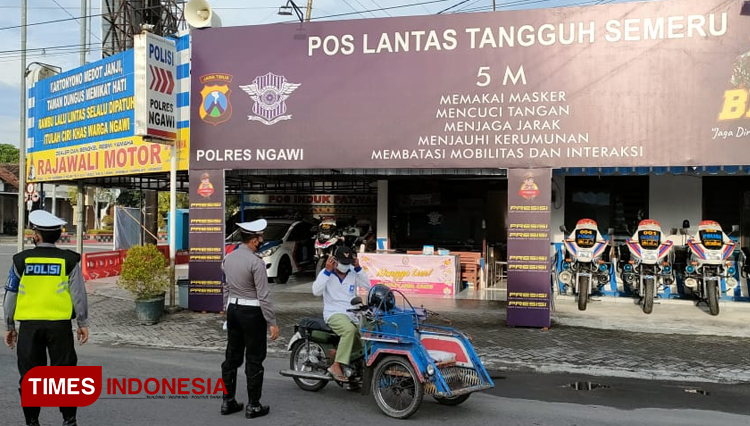 Anggota Satlantas Polres Ngawi membagikan masker kepada warga yang melintas di depan Pos Tangguh Semeru. (Foto: Humas Polres Ngawi/ TIMES Indonesia) 