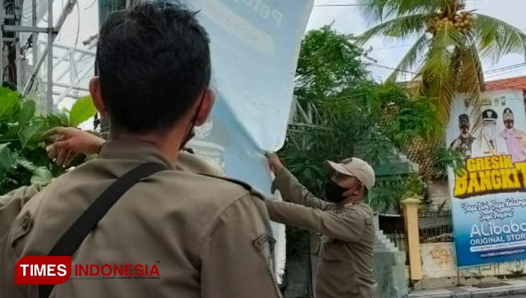 Petugas Satpol PP saat membersihkan reklame di pusat kota (Foto: Akmal/TIMES Indonesia).