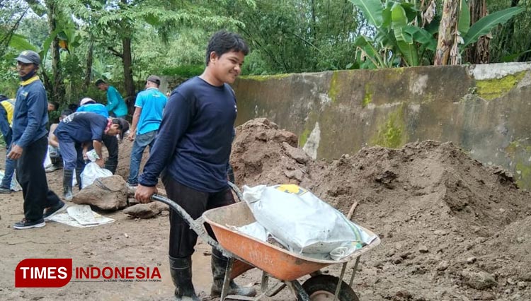 Warga dan petugas BBWS Bengawan Solo memasang sand bag di lokasi tanah ambles. (Foto: Romi Tri Setyo Widodo/TIMESIndonesia)