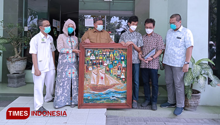 Pelukis Muda Aril saat memberikan lukisan secara simbolis yang diterima para Direksi RS Ibnu Sina Kabupaten Gresik. (FOTO: Akmal/TIMES Indonesia)