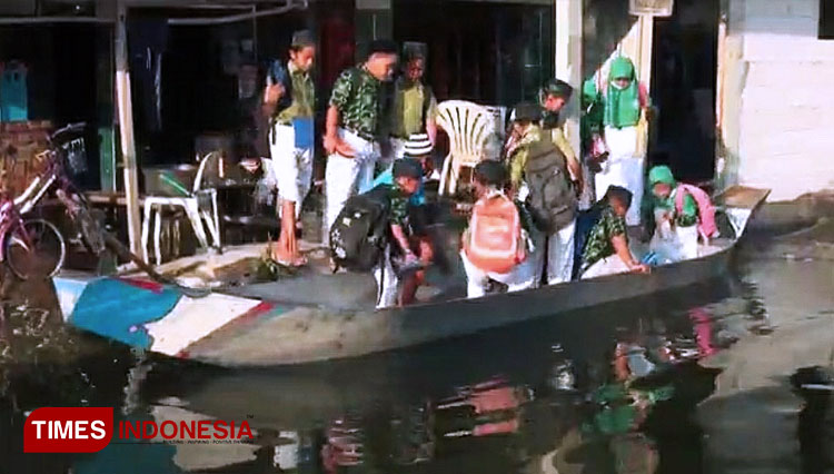 Sejumlah pelajar madrasah naik ke perahu yang akan mengantarkan mereka pergi ke sekolah, akibat banjir yang melanda kawasan Bengawan Njero Lamongan, Rabu (3/3/2021). (FOTO: MFA Rohmatillah/ TIMES Indonesia)