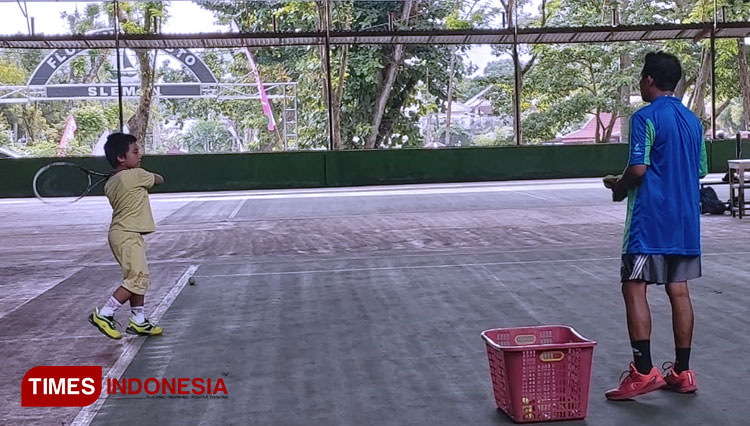 Pelatih Tenis, Tolu Setiyawan ketika mengajarkan teknik tenis yang benar kepada anak didiknya. (FOTO: Fajar Rianto/TIMES Indonesia)