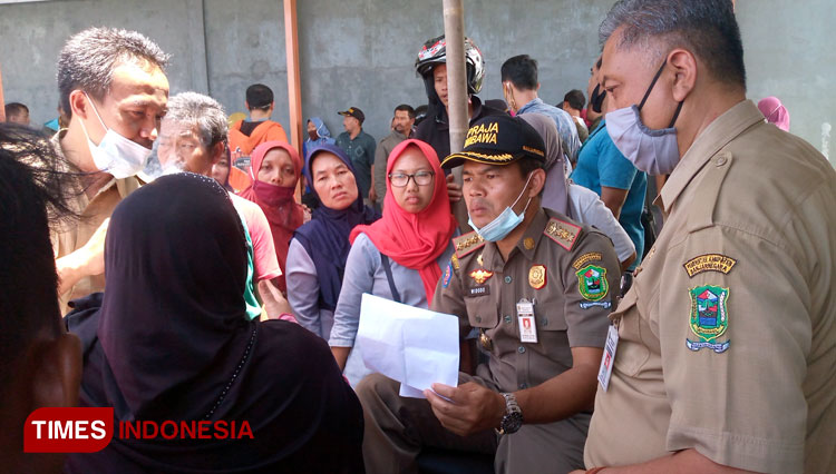 Kasatpol PP Esti Widodo dan PLT kaindagkop Abdul Suhendi dikelilingi pedagang usai undian lapak berjualan di Pasar Salak. (FOTO: Muchlas Hamidi/TIMES Indonesia)