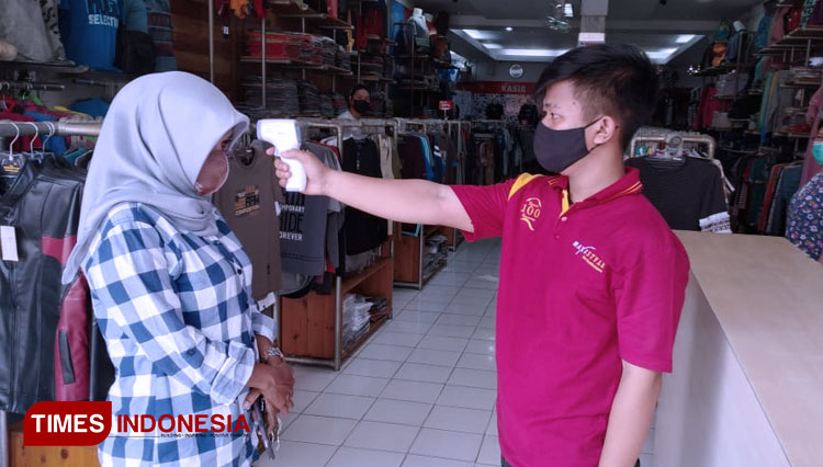 Karyawan toko mengecek suhu pengunjung dengan Thermogun (Foto:Susi/TIMES Indonesia)