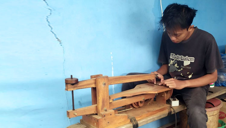 Muhammad Mujib works with the key chain maker device at his own house in Pacitan. (Photo: A Craft for TIMES Indonesia)