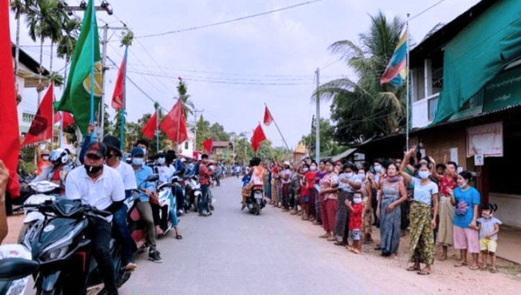 Para demonstran memegang bendera saat mereka duduk di atas sepeda motor selama protes di Launglone, distrik Dawei, Myanmar (26/3/202). (FOTO: Reuters)