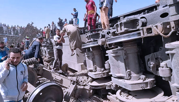 Tim penyelamat berkumpul di sekitar reruntuhan dua kereta penumpang yang bertabrakan di distrik Tahta di Mesir selatan. (FOTO: France24/ AFP)